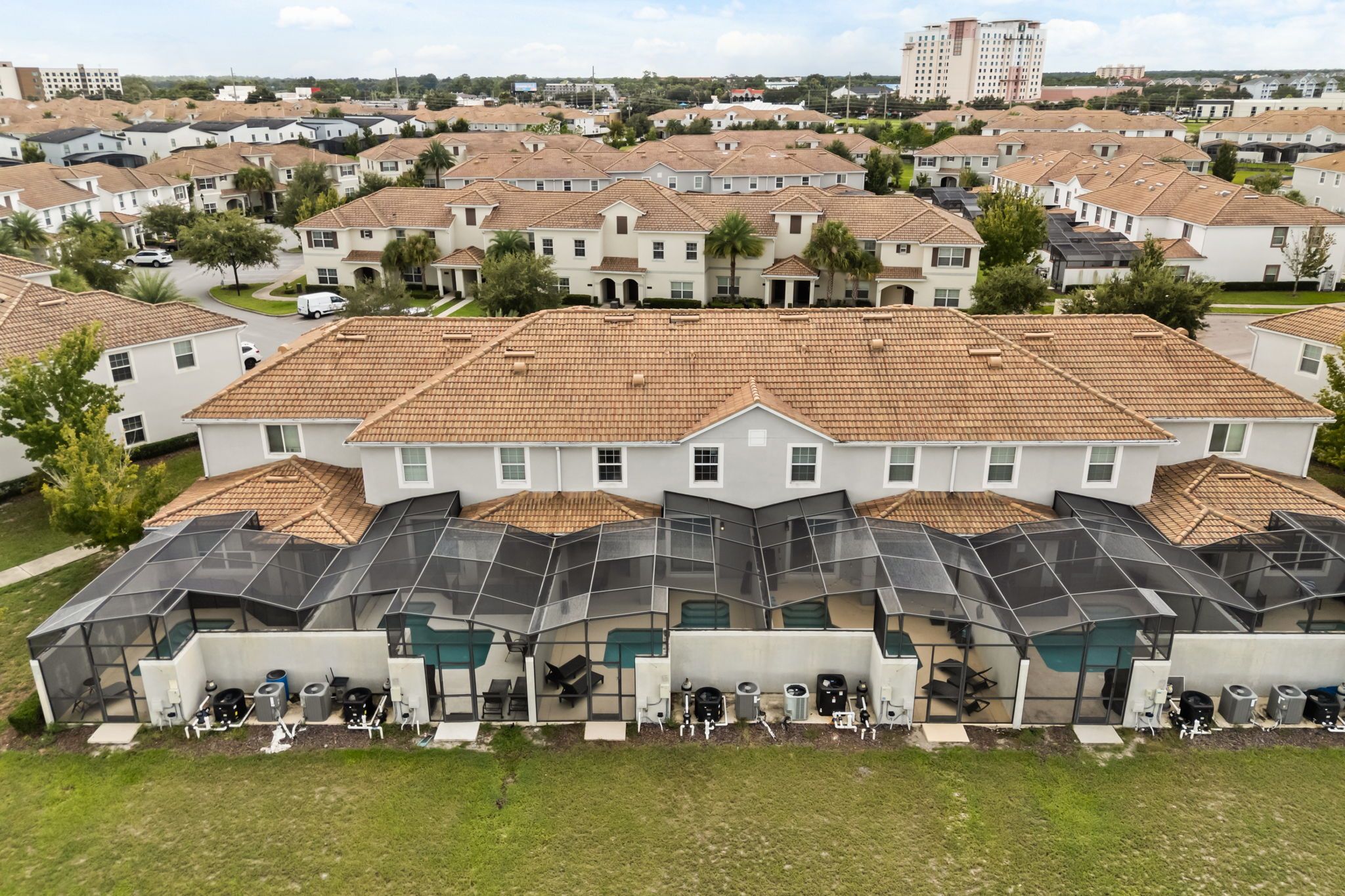 A residential area with multiple houses, a large building with a flat roof, and a covered outdoor area with equipment.