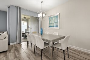 Un comedor con una mesa y sillas, un ventilador de techo y un cuadro en la pared.