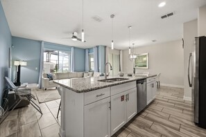 A modern kitchen with a central island, white cabinetry, and a stainless steel refrigerator. - 4 BD/ 3 BA/ Storey Lake (4887 RC) (Kissimmee)