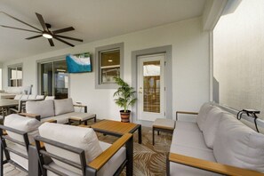 Una sala de estar moderna con ventilador de techo, un ventanal grande, una planta en maceta y un sofá.