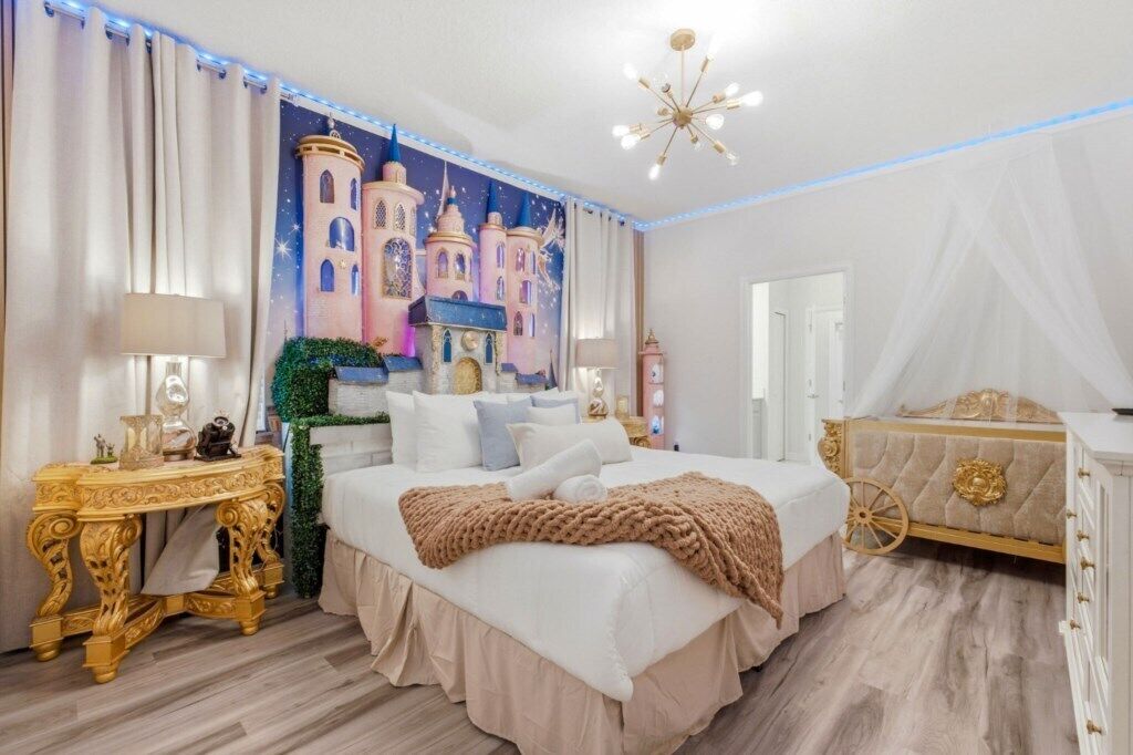 A bedroom with a large bed, a decorative headboard, a nightstand, and a wall mural.