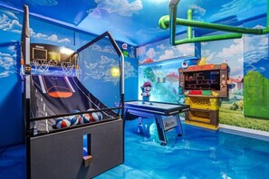 Un espacio de juegos interior con cancha de baloncesto, mesa de billar y máquina de garrapatas.