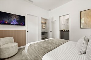 A hotel room with a bed, a chair, a TV mounted on the wall, and a bathroom visible through an open door. - 3 BD/ 3 BA/ The Hub at Westside Reserve (3227 SW) (Kissimmee)