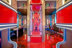 A futuristic interior with a central red-lit display, metallic walls, and a reflective floor. - 7 BD / 5.5 BA / Windsor Cay 1091 OP (Clermont)