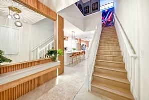 Ein modernes Interieur mit einer Treppe, die zu einer Bar, einem Empfangsbereich und einer Küche im Hintergrund führt.