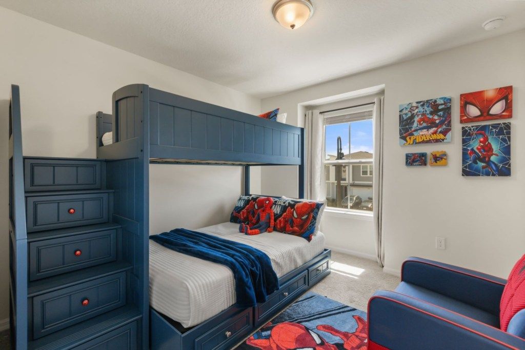 A bunk bed with drawers, a window with a view, and Spider-Man themed decorations.
