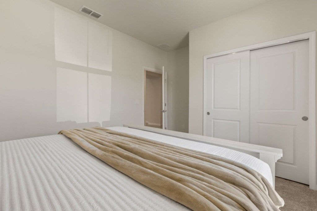 A bedroom with a bed, a bedside table, and a wardrobe.
