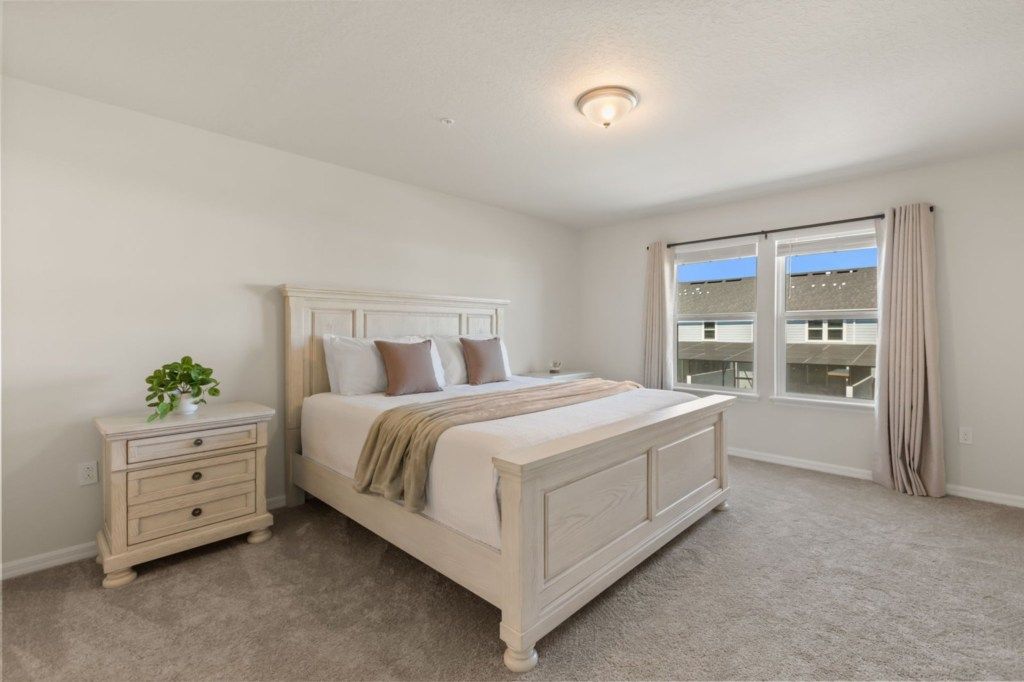 A bedroom with a bed, nightstand, and window.