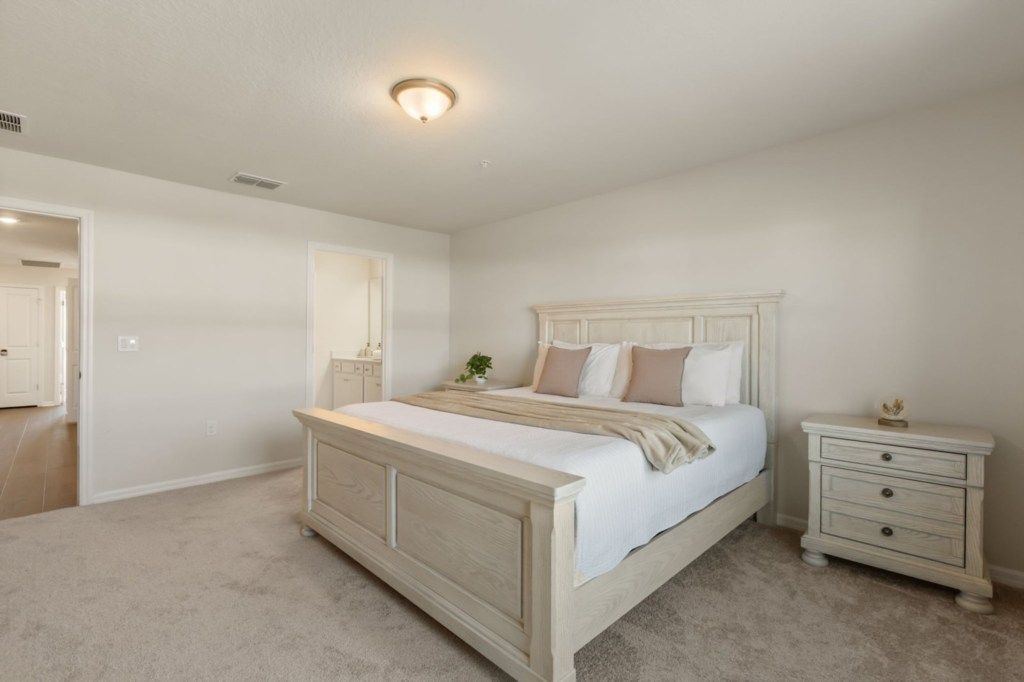A bedroom with a large bed, a nightstand, a dresser, and a ceiling light.