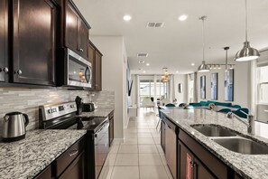 A modern kitchen with granite countertops, stainless steel appliances, and dark wooden cabinets. - 7 BD / 5.5 BA / Windsor Island Resort 3409 LW (Davenport)