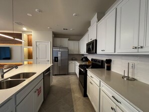 A modern kitchen with white cabinetry, stainless steel appliances, and a built-in microwave. - Resort-style 5 BD/ 4.5 BA/ Windsor Cay - 16209 PF (Clermont)