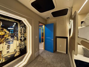 A room with bunk beds, a door leading to another room, and a wall with a space-themed mural. - Resort-style 5 BD/ 4.5 BA/ Windsor Cay - 16209 PF (Clermont)