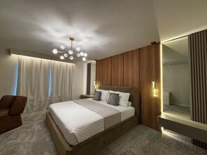 A modern bedroom with a large bed, a wooden headboard, a bedside table, and a mirror. - Resort-style 5 BD/ 4.5 BA/ Windsor Cay - 16209 PF (Clermont)