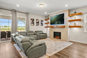 Una sala de estar moderna con un sofá modular, una chimenea y un televisor grande.