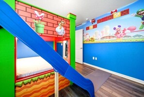 Ein Kinderspielbereich mit Rutsche und Wandgemälde eines Videospielcharakters.