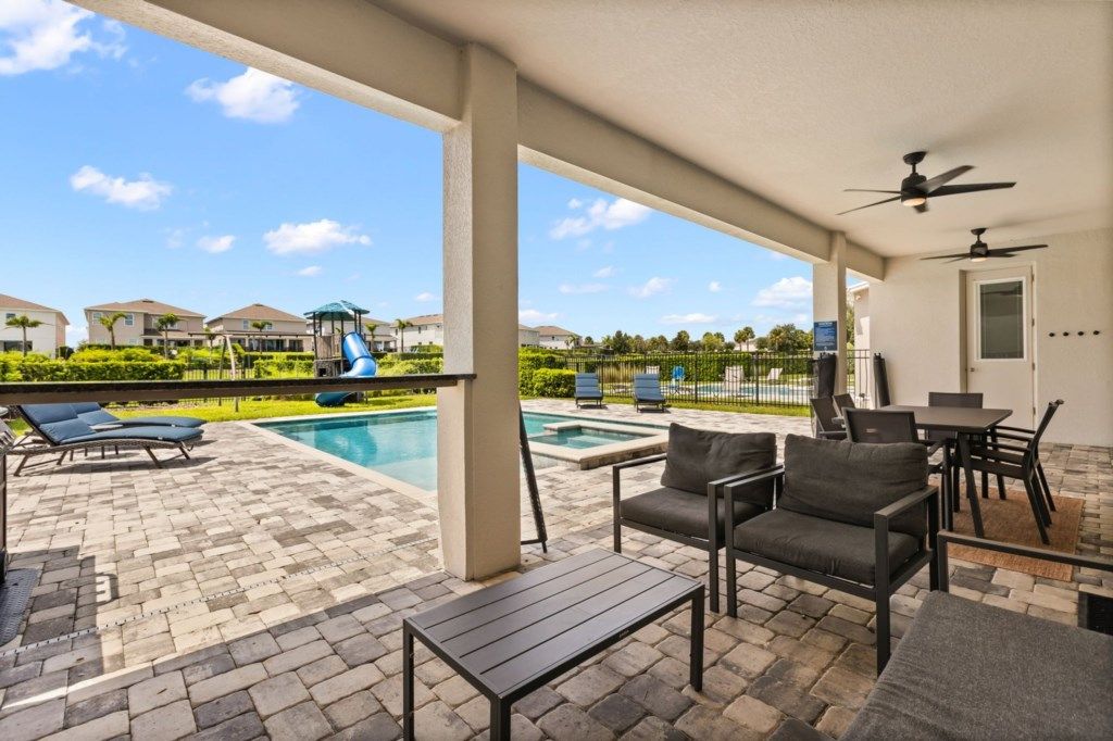 A covered outdoor area with a pool, lounge chairs, and a table.