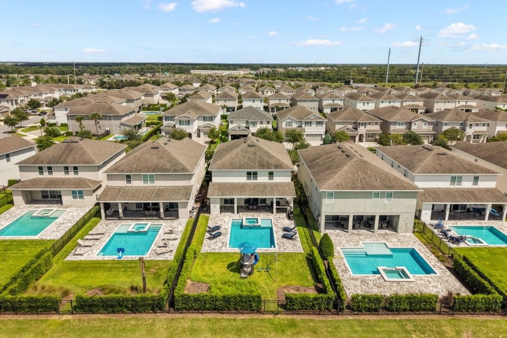 A residential area with multiple houses, each with a swimming pool and a well-maintained lawn.