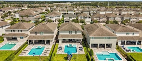 Un barrio residencial con varias casas, cada una con piscina y césped cuidado.