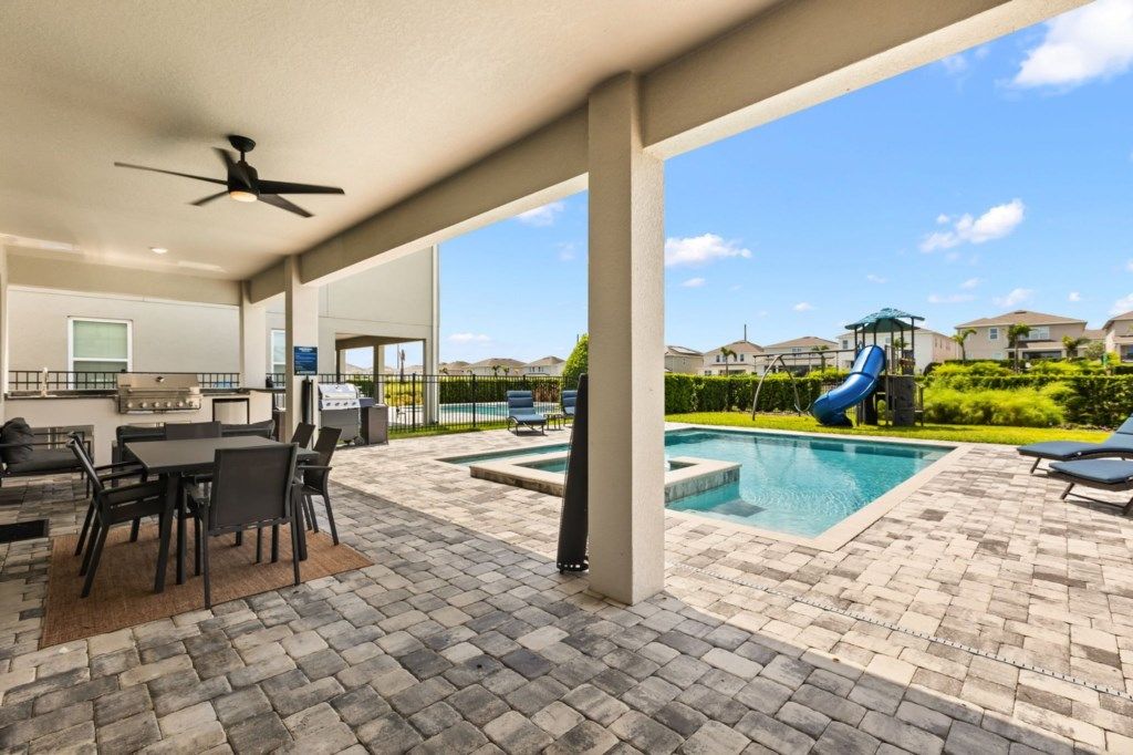 An outdoor patio with a pool, a barbecue area, and a slide.