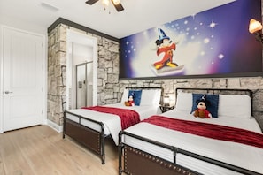 A hotel room with two beds, a stone accent wall, a large Disney-themed mural, and a ceiling fan. - 7 BD / 6.5 BA / Encore Resort at Reunion 256 AA (Kissimmee)