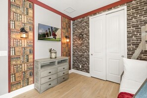 A room with a brick wall, a white door, a wooden dresser, and a framed picture on the wall. - 7 BD / 6.5 BA / Encore Resort at Reunion 256 AA (Kissimmee)