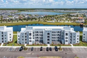 A multi-story residential building with a parking lot in front. - 2 BD/ 2 BA/ Storey Lake (3151-302 PC) (Kissimmee)