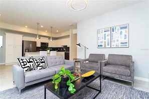 A modern living room with a sofa, armchair, coffee table, and artwork on the wall. - 2 BD/ 2 BA/ Storey Lake (3151-302 PC) (Kissimmee)