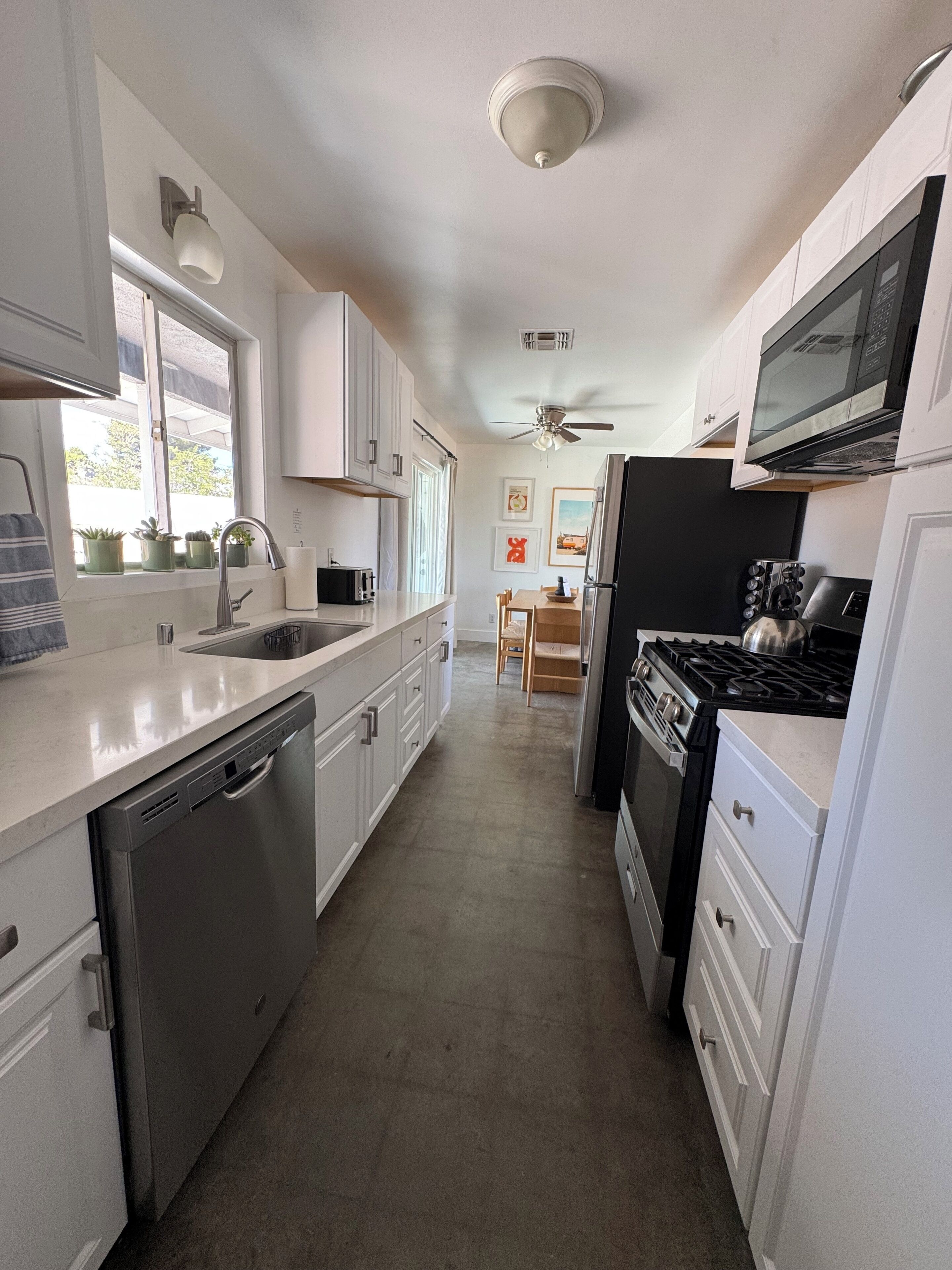 A kitchen with white cabinets, a dishwasher, a stove, and a microwave.