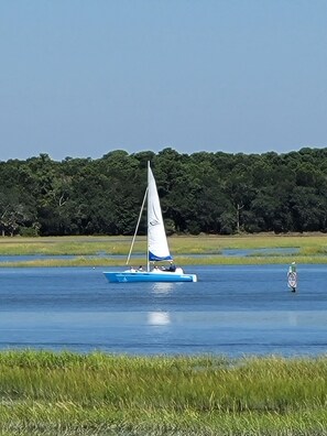 Ein Segelboot auf ruhigem Wasser, im Hintergrund eine bewaldete Küste.
