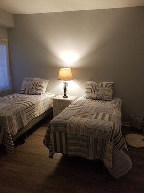 Une chambre avec deux lits, une lampe de chevet et un petit tapis rond.