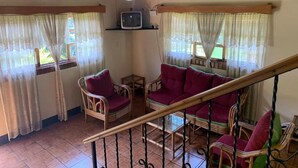 A living room with wicker furniture, a television, and a staircase. - Hotel Posada Kamol Bey (Panajachel)