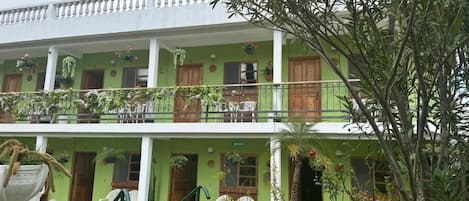 A two-story building with balconies, potted plants, and outdoor seating.