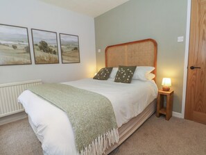 Ein Schlafzimmer mit einem Bett, einem Nachttisch mit Lampe und drei Landschaftsbildern an der Wand.
