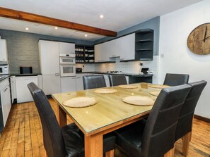 Eine moderne Küche mit weißen Schränken, einem Holzespeise-Tisch mit vier Stühlen und einer Uhr an der Wand.