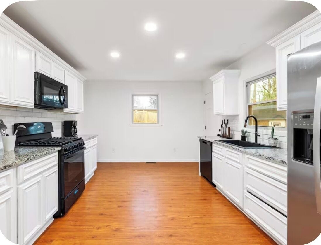 A kitchen with white cabinets, a stainless steel refrigerator, a microwave, and a stove.
