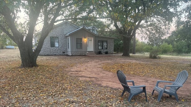 A stone house with a porch, two Adirondack chairs, and a leaf-covered ground. - 3-Acre Wildlife Retreat : Sleeps & Dines 12 : 5 mi to Duncan: 26 mi to Fort Sill (Marlow)