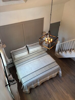 A bedroom with a bed, a hanging light fixture, and a staircase. - 3-Acre Wildlife Retreat : Sleeps & Dines 12 : 5 mi to Duncan: 26 mi to Fort Sill (Marlow)