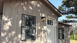 A house with a stone foundation, a white door, and two windows with black frames. - 3-Acre Wildlife Retreat : Sleeps & Dines 12 : 5 mi to Duncan: 26 mi to Fort Sill (Marlow)