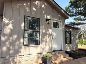 A house with a stone foundation, a white door, and two windows with black frames. - 3-Acre Wildlife Retreat : Sleeps & Dines 12 : 5 mi to Duncan: 26 mi to Fort Sill (Marlow)