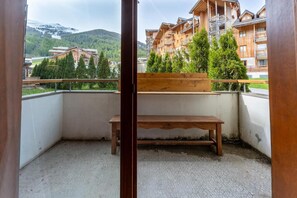 A balcony with a wooden bench, a white wall, and a view of a mountain and buildings. - 40m from ski slopes, fitness, swimming pool, sauna, balcony, tv, ski locker, 43m², Les Orres (Les Orres)