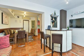 Een ruimtelijk ingerichte leefruimte met een eethoek, een kitchenette en een bar.