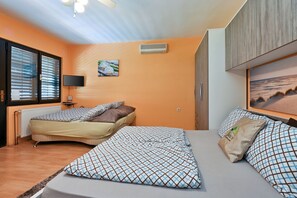 Een slaapkamer met twee bedden, een flatscreen televisie, een schilderij en een raam met jaloezieën.