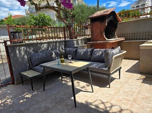 An outdoor seating area with a table and chairs, a brick oven, and a view of the surrounding area. - One Bedroom Apartment Lux 2 with Balcony (Okrug Gornji)