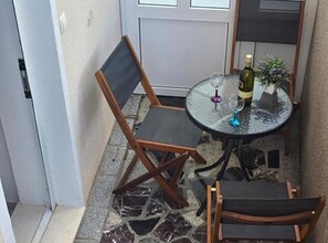A small outdoor seating area with a table, two chairs, a wine bottle, and a glass. - One Bedroom Apartment Lux 2 with Balcony (Okrug Gornji)