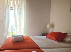 Een hotelkamer met een bed, een lamp en uitzicht op het groen.