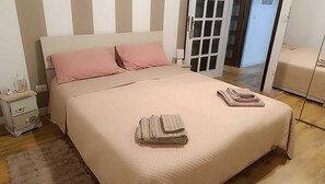 A neatly made bed with pink pillows, a bedside table with a lamp, and a folded towel on the bed. - Elegant vacation home in the Gulf of Asinara, ideal for families. (Sorso)