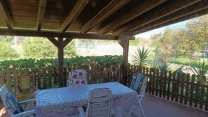 Eine Terrassenanlage im Freien mit einer Holz-Pergola, einem Tisch mit Stühlen und einem Holzzaun.