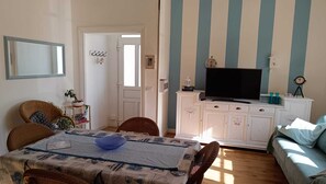A living room with a television, sofa, and dining area with chairs and a table. - Elegant vacation home in the Gulf of Asinara, ideal for families. (Sorso)