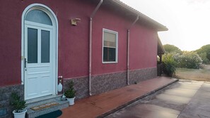 A red house with a white door, a small window, and a porch with steps leading to the entrance. - Elegant vacation home in the Gulf of Asinara, ideal for families. (Sorso)