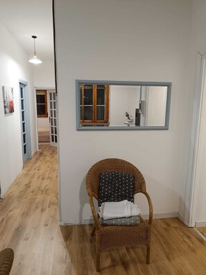 Ein Zimmer mit Korbsessel, Spiegel und Holzboden.